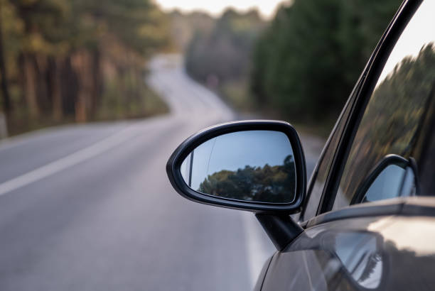 istock Car rear view mirror on wooded rural road 1221825038