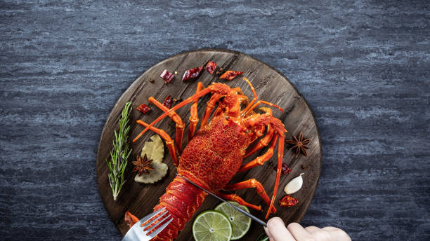 istock Cooked boiled lobster, delicious dinner seafood meal set with knife and fork on black stone slate background, restaurant menu design, top view, overhead 1221825836