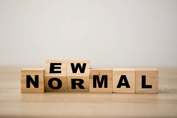 hand flipping wooden block cubes for new normal wording. the world is changing to balance it into new normal include business , economy , environment and health. - going into imagens e fotografias de stock