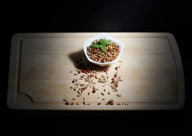 Beans and rye with mint leaves on a white bowl, on a wooden chopping board, illuminated by direct sunlight