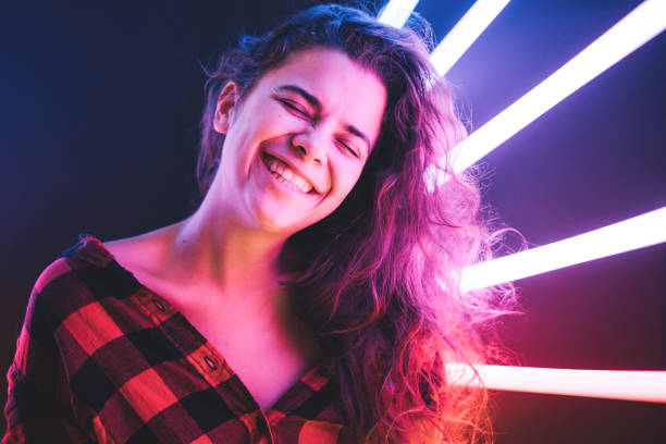istock Cheerful cute smiling curly girl at neon violet background. 1221836103