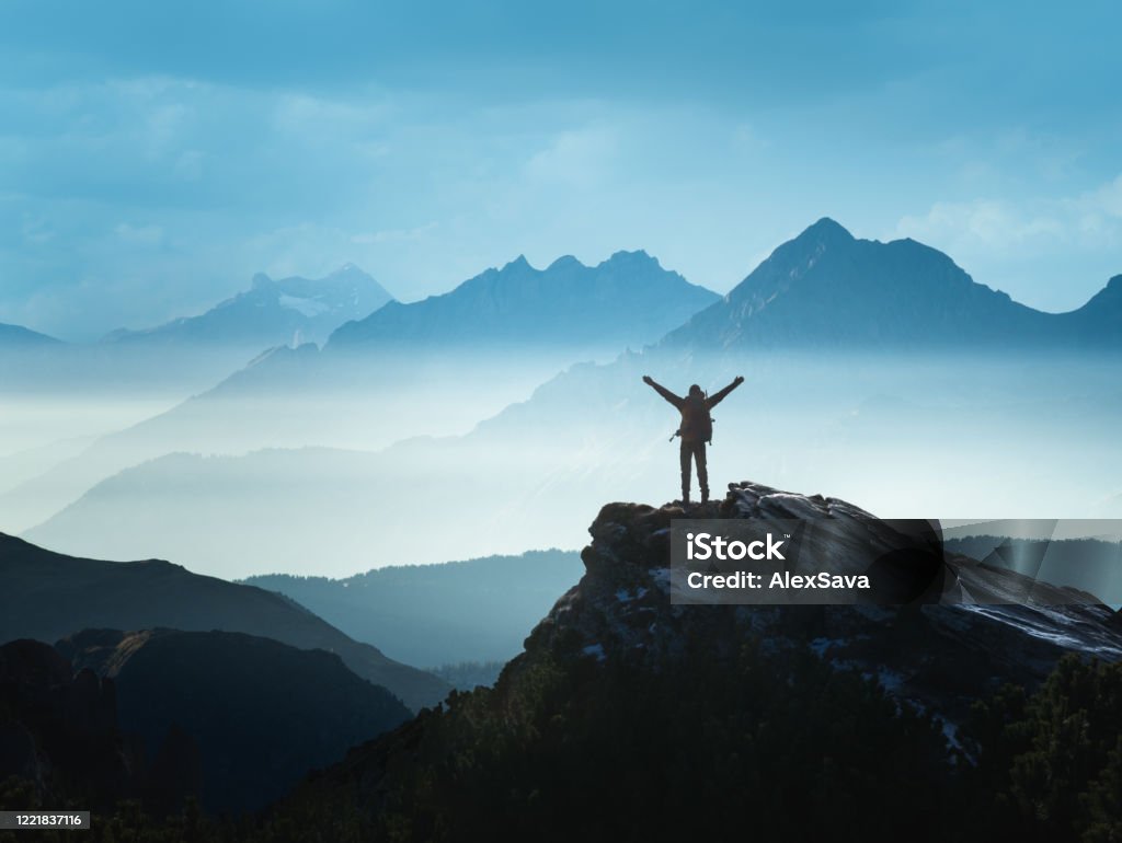 Positive man celebrating success Positive Man standing on top of the mountain with arms raised celebrating his success Mountain Stock Photo