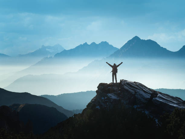 Positive man celebrating success Positive Man standing on top of the mountain with arms raised celebrating his success dramatic landscape photos stock pictures, royalty-free photos & images