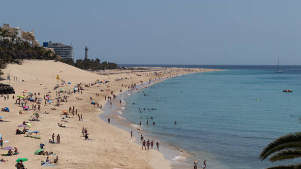 istock Yellow sand beach with tourists, dune and lighthouse 1221837829