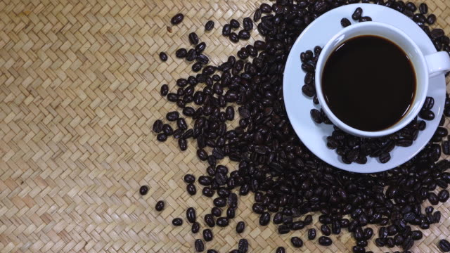 Cup of coffee and coffee beans on wooden background.