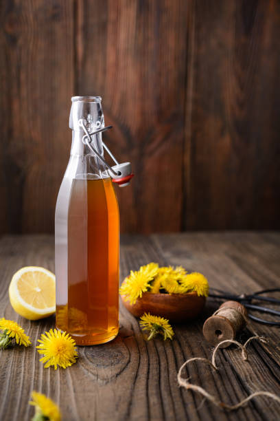 Homemade healthy dandelion syrup in a glass bottle, decorated with fresh flowers with copy space stock photo