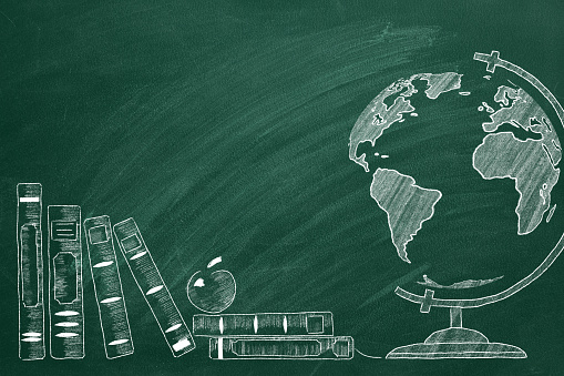 Rotating globe and school books are drawn with chalk on a blackboard.