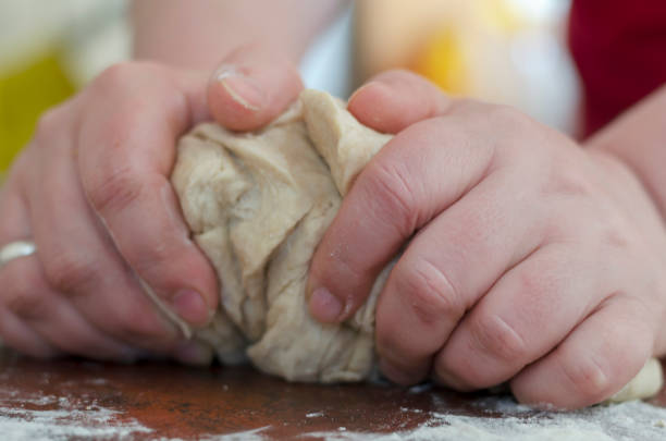 istock Female hands knead the dough on the kitchen table. 1221841277