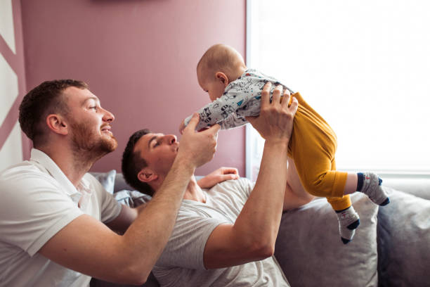 Homosexual couple is taking care of a little baby stock photo