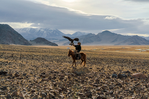 A Kazakh eagle hunter and a young boy on their horses at his Golden Eagle at the Sagsai Golden Eagle Festival held on 17th-18th September 2023, near the small town of Sagsai, in the Bayan-Ulgii province of Western Mongolia. Set in the Altai Mountain range, the nomadic eagle hunters, dressed in traditional fur and embroidered clothing, gather to compete with their eagles, in various competitions that show the skill and bond between the hunter and their eagle.