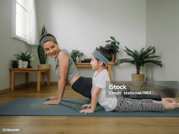 Mother Doing On Yoga Mat With Little Daughter At Home Stock Photo - Download Image Now