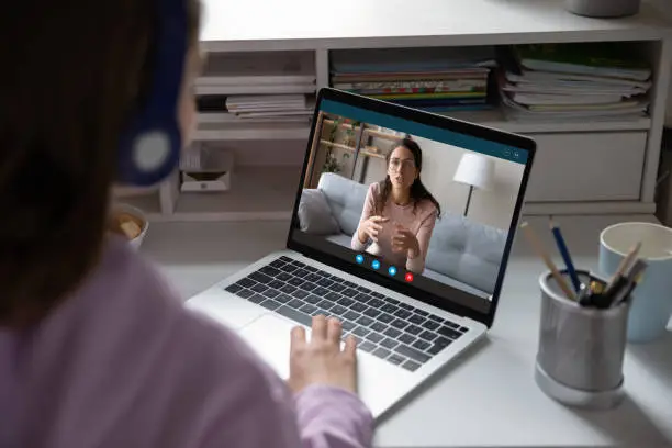 Photo of School girl student studying with online teacher on computer screen