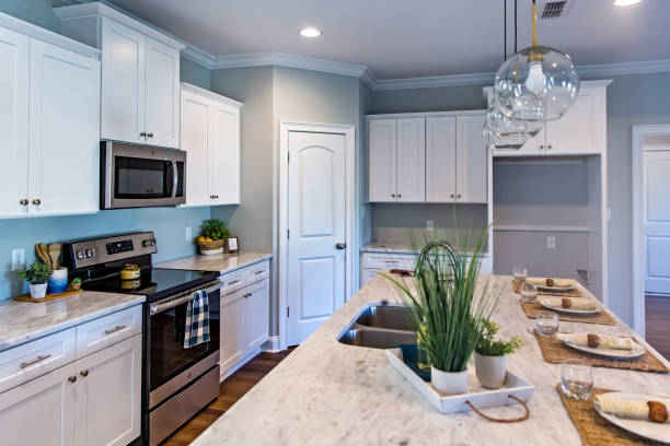 istock Open floor plan kitchen in a new construction empty house that has just been completed with white cabinets, pendant lighting, a bar area and hardwood floors 1221847506