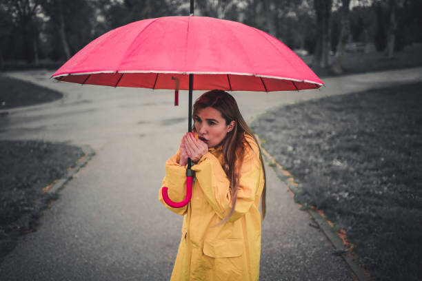 istock Woman under the umbrella warms her hands with breath 1221847579