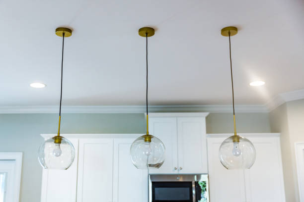 istock Pendant lighting in an open floor plan kitchen in a new construction empty house that has just been completed with white cabinets 1221847580