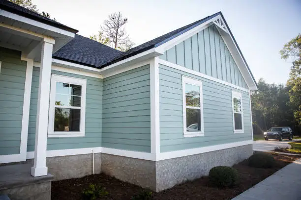 Photo of Front view of a brand new construction house with blue siding, a  ranch style home with a yard