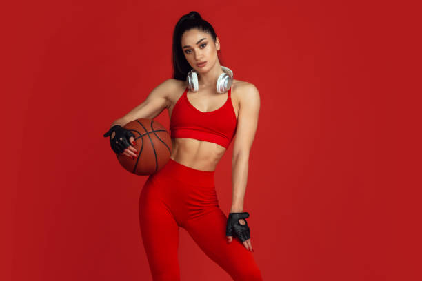 istock Beautiful young female athlete practicing on red studio background, monochrome portrait 1221848795