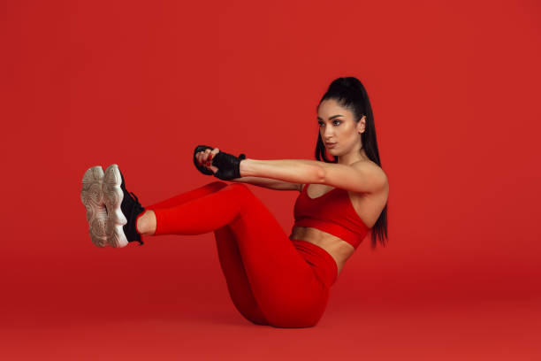 istock Beautiful young female athlete practicing on red studio background, monochrome portrait 1221848797