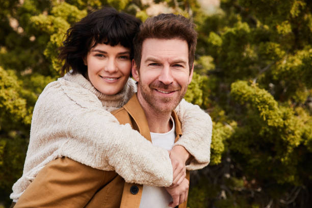 istock Smiling man carrying his girlfriend on his back outside 1221850664