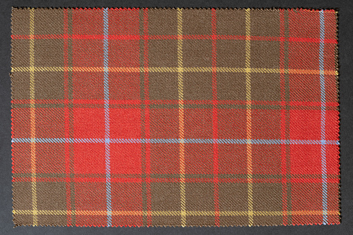 Close up of Scottish tartan called Burnett Ancient on a charcoal colored background.