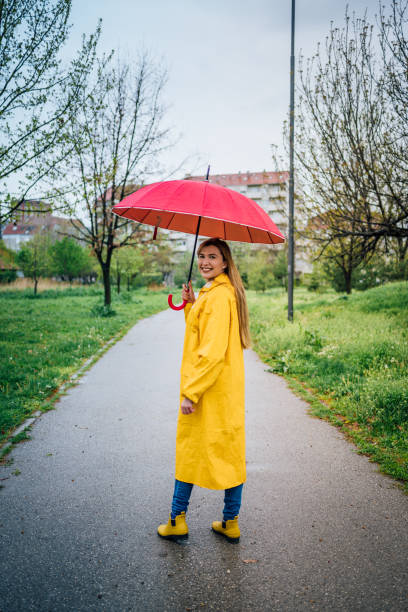istock Woman in yellow raincoat and rain boots 1221851536