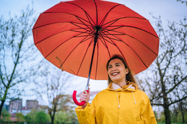 istock Woman with red umbrella standing outdoors in the rain 1221852822