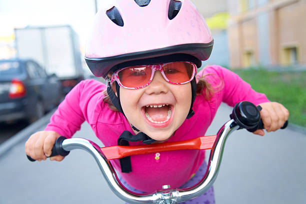 funny girl and bicycle Portrait of a playful funny girl in a pink safety helmet on her bike helmet stock pictures, royalty-free photos & images