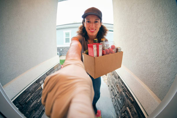 Grocery Delivery Person A young woman delivering groceries to a home in the evening. fish eye lens stock pictures, royalty-free photos & images