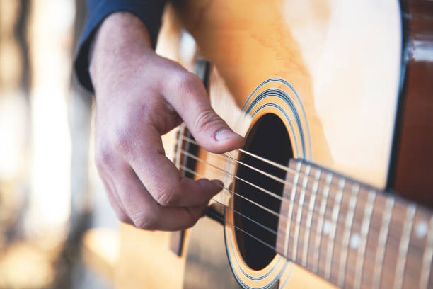istock Young man plays guitar outdoors 1221862183