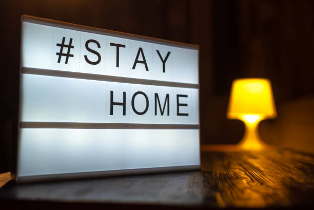 istock Lightbox sign with text hashtag STAY HOME with turned on table lamp on the background. COVID-19. Stay home save concept 1221862313