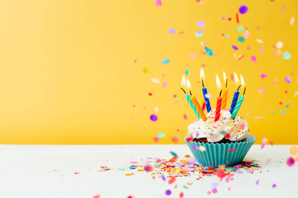 birthday cupcake with many candles and confetti on yellow background - copy space single object confetti nobody imagens e fotografias de stock