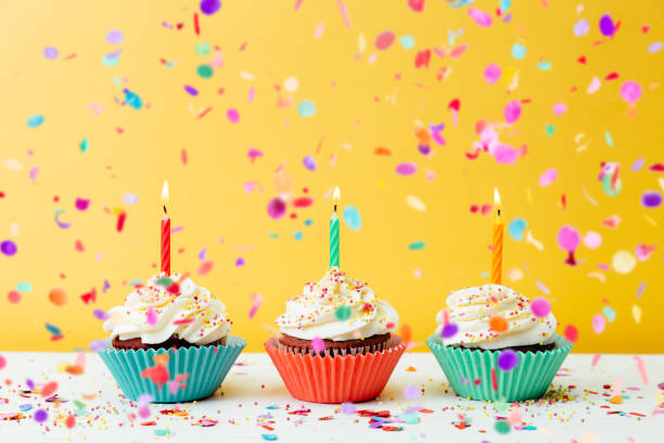 istock Birthday cupcakes with confetti on yellow background 1221862770