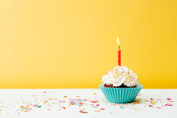 birthday cupcake on yellow background - copy space single object confetti nobody imagens e fotografias de stock