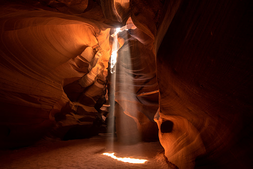 Turbulent waves of colorful sandstone created by natural erosion of Colorado Plateau enhances beauty of Antelope Canyon on Navajo Tribal Park near Page Arizona. Sunbeam through the rocks at noon.