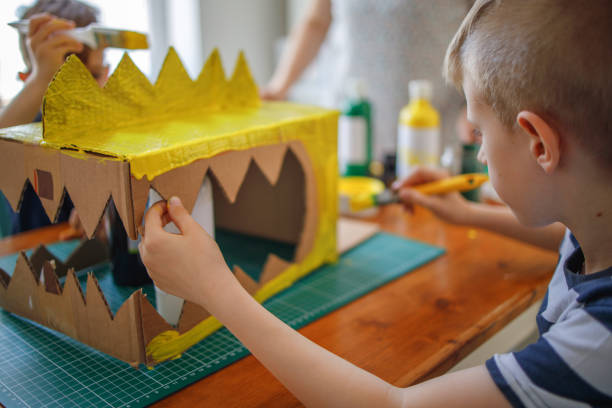 istock Boy painting a cardboard dinosaur costume 1221866703