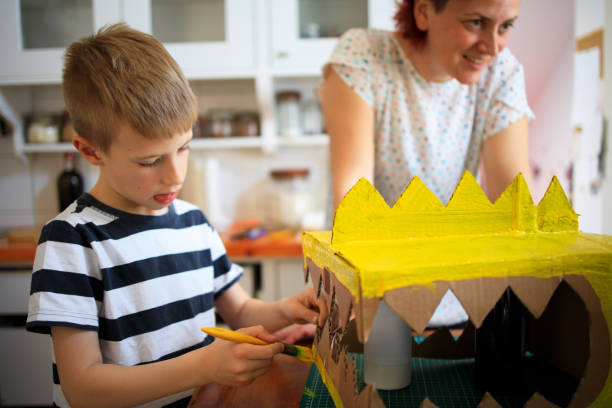 istock A Boy painting a cardboard dinosaur costume 1221867931