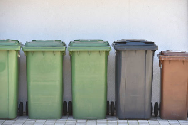istock Green trash cans are standing against the wall. Garbage containers for sorting garbage in a European city 1221868337