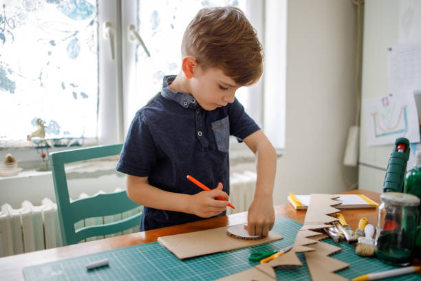 istock Smiling boy making a cardboard dinosaur costume 1221868711