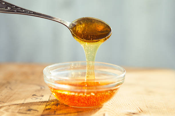 istock Honey dripping from spoon in the cup 1221869406