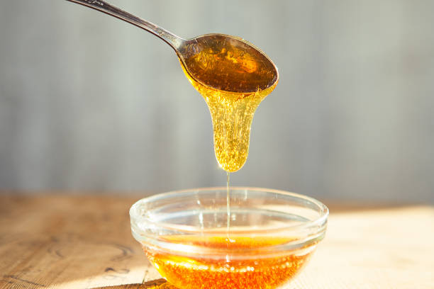 istock Honey dripping from spoon in the cup 1221869468