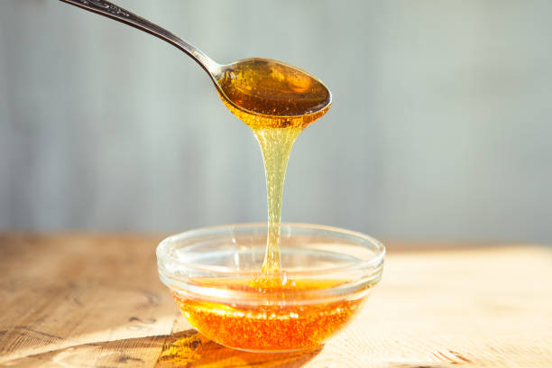 istock Honey dripping from spoon in the cup 1221869486