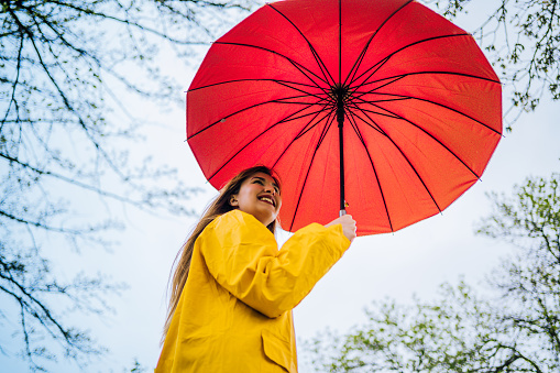 Happy young woman under red umbrella in rain