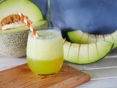A glass of green melon juice or honeydew with fresh melon fruit for healthy drink concept.
