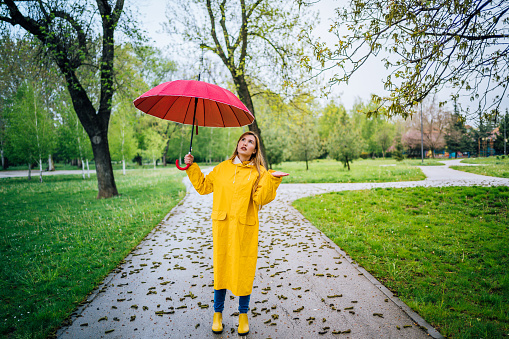 Young caucasian woman with umbrella checks if it is raining