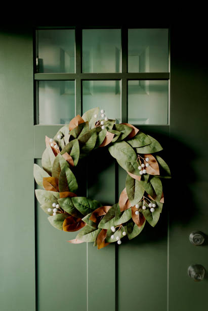 Porta d'ingresso in stile artigiano dipinta di un verde cacciatore con corona di magnolia - foto stock