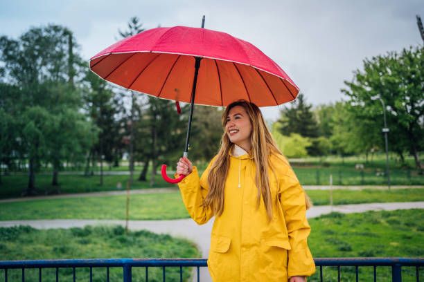 istock Woman with red umbrella standing outdoors in the rain 1221871382