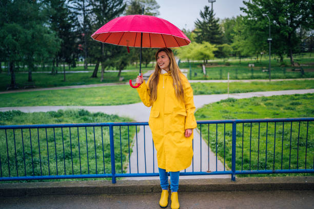 istock Woman with red umbrella standing outdoors in the rain 1221871937