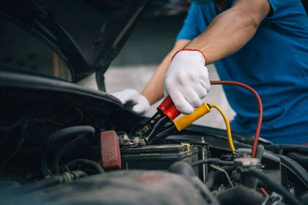 os cabos de reforço e a bateria descarregada, carregando o carro da bateria com cabos de jumper de eletricidade. - antepasto fotos - fotografias e filmes do acervo