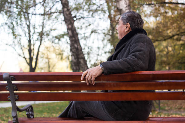 istock Senior man sitting on bench in the park 1221872859