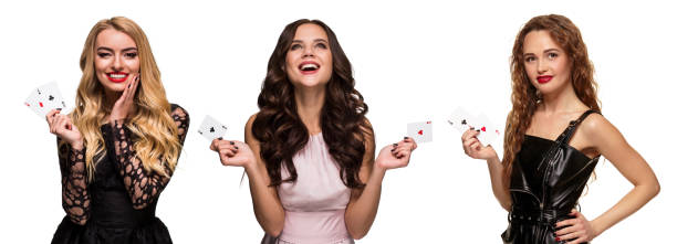 three girls with make-up and hairstyles, in pink and black dresses, jewelry. smiling, showing aces, posing isolated on white. poker, casino. close-up - gambling chip poker casino ace imagens e fotografias de stock